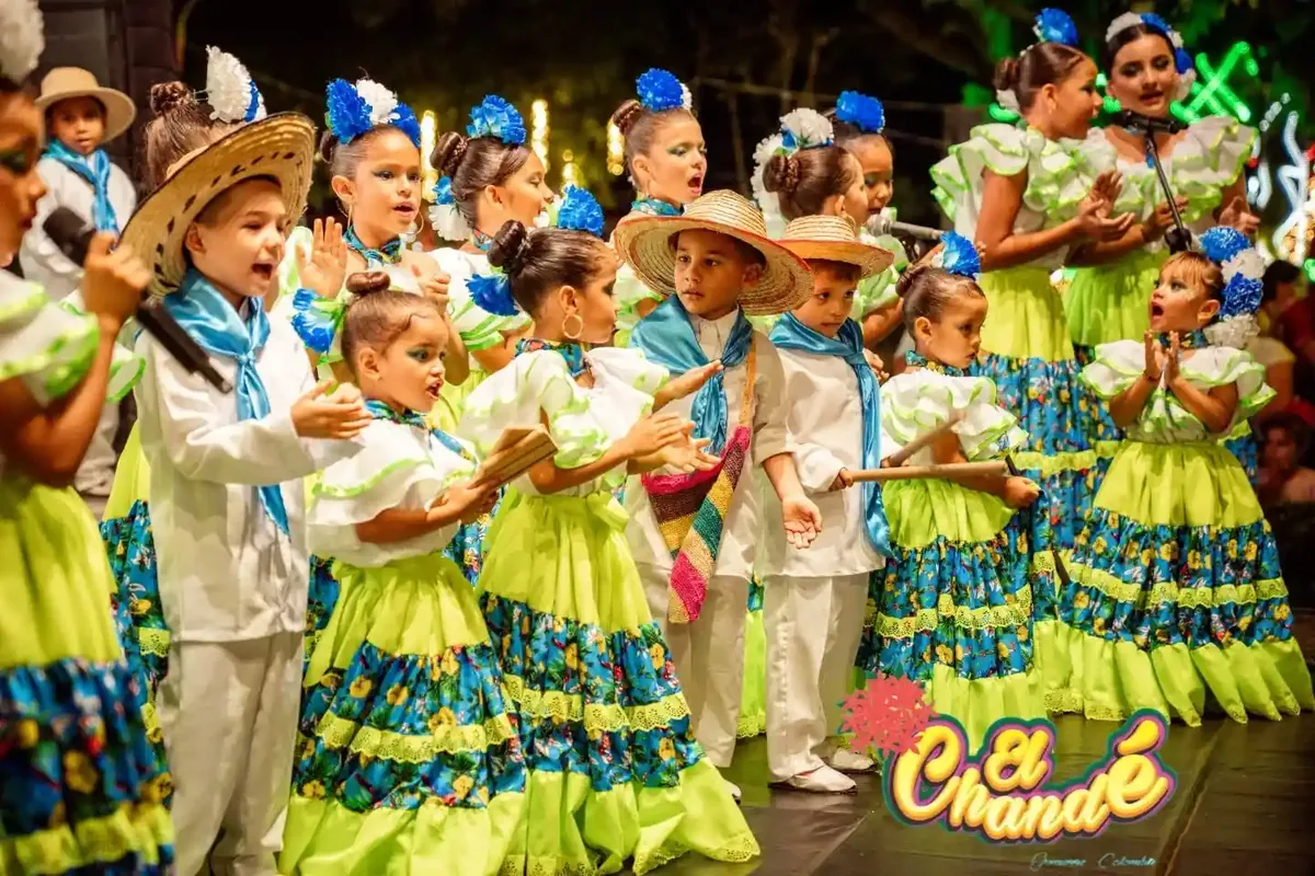Grupo de niñas y niños con camisas blancas y pañoletas rojas sosteniendo tambores.