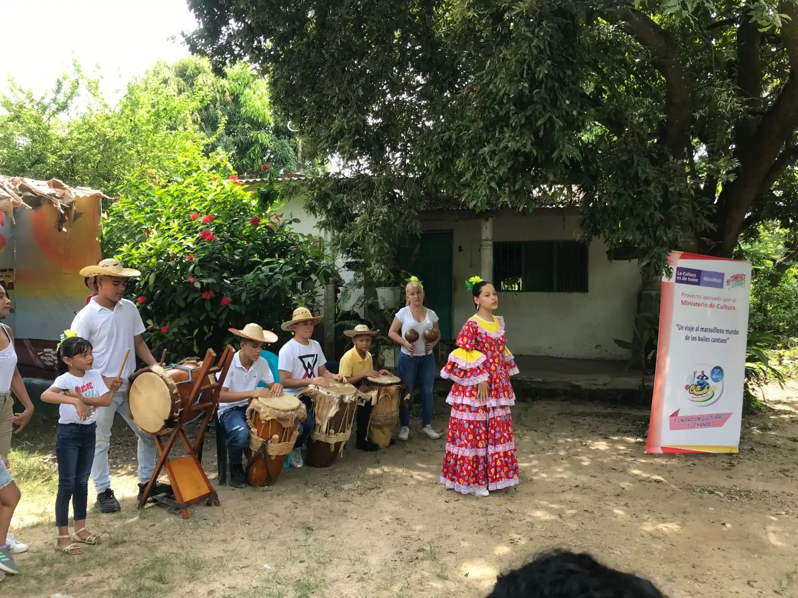 Niños con tamboras y una bailadora con vestido tradicional en el patio de una casa de Gamarra.